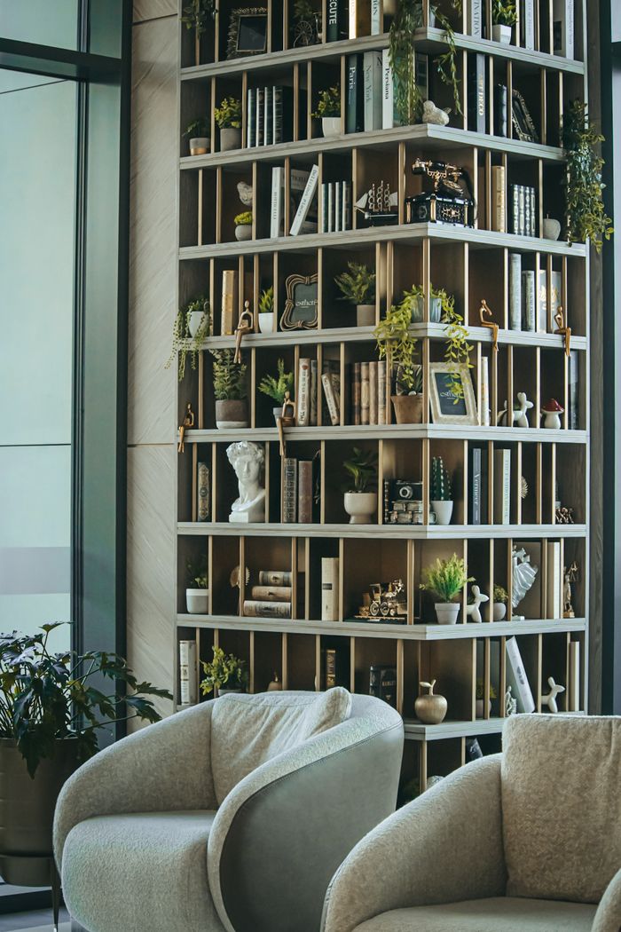 A modern lounge featuring a unique bookshelf filled with books and decorative plants, creating a cozy atmosphere.